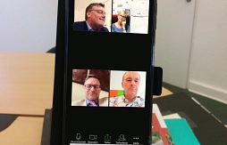 Auf dem Bildschirm eines Smartphones sind die Video-Konferenzteilnehmer Thomas Berling, Raphael Kürzinger, Achim Haming und Chris-Dore Trampel zu sehen.